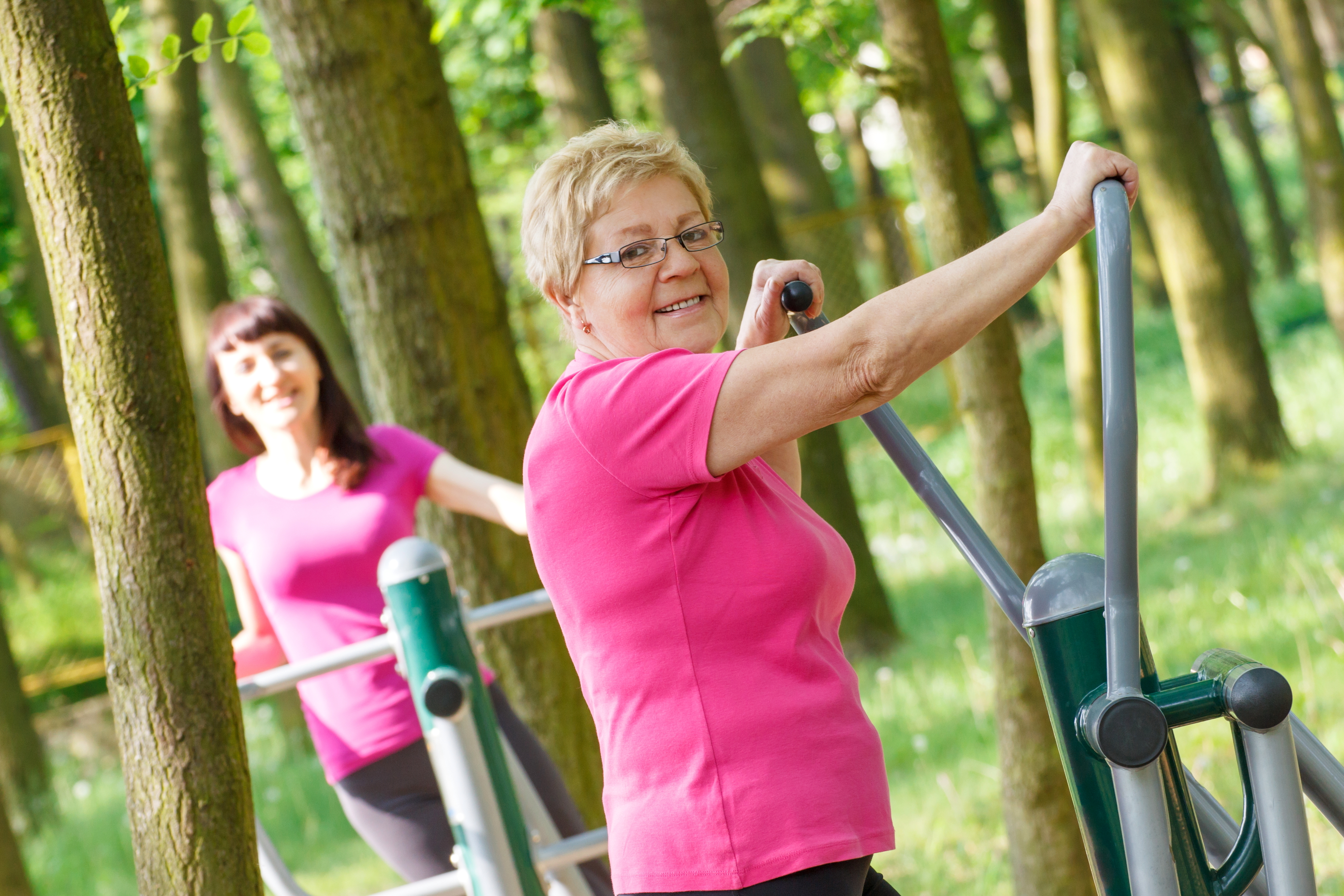 Two women exercising on equipment outdoors